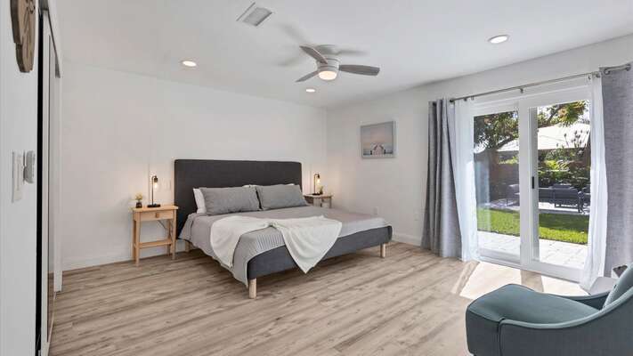Primary bedroom with king bed, attached bathroom, access to backyard, and 50-inch Smart TV